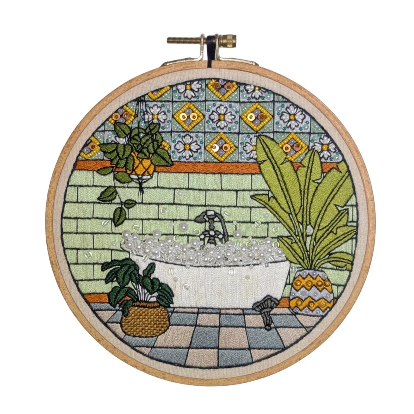 Embroidery hoop with a colorful depiction of a bathroom scene on a tiled background