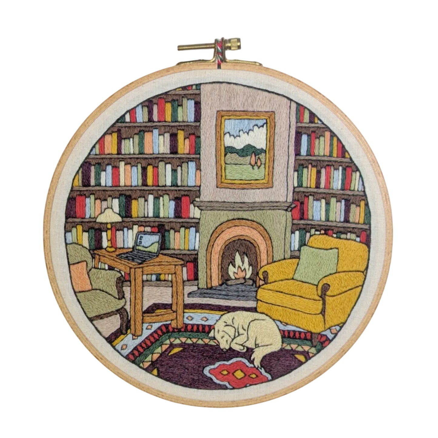 Embroidery hoop with a cozy living room scene including a fireplace, books, and a cat.