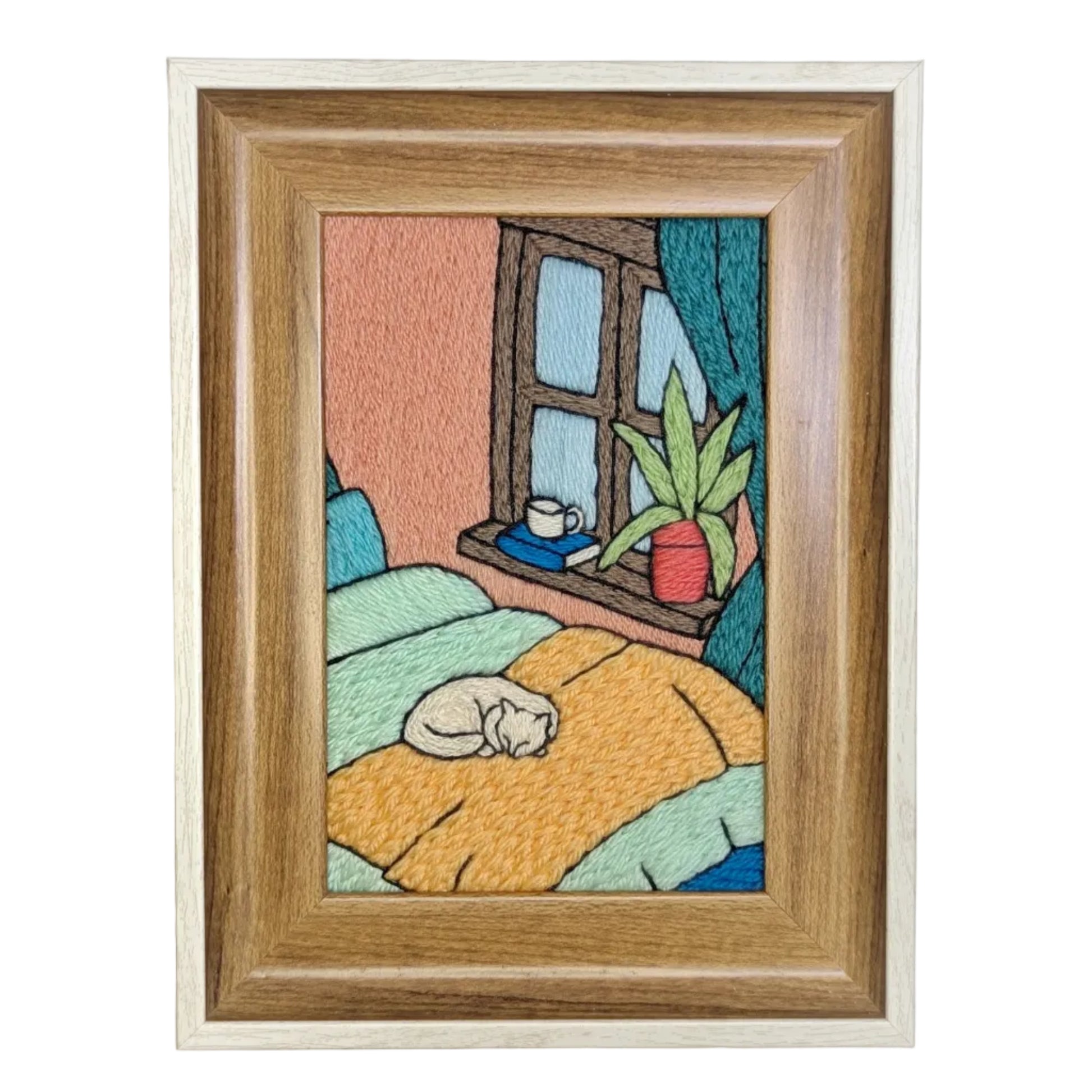 Framed artwork of a cat sleeping on a bed with a window and plant in the background.