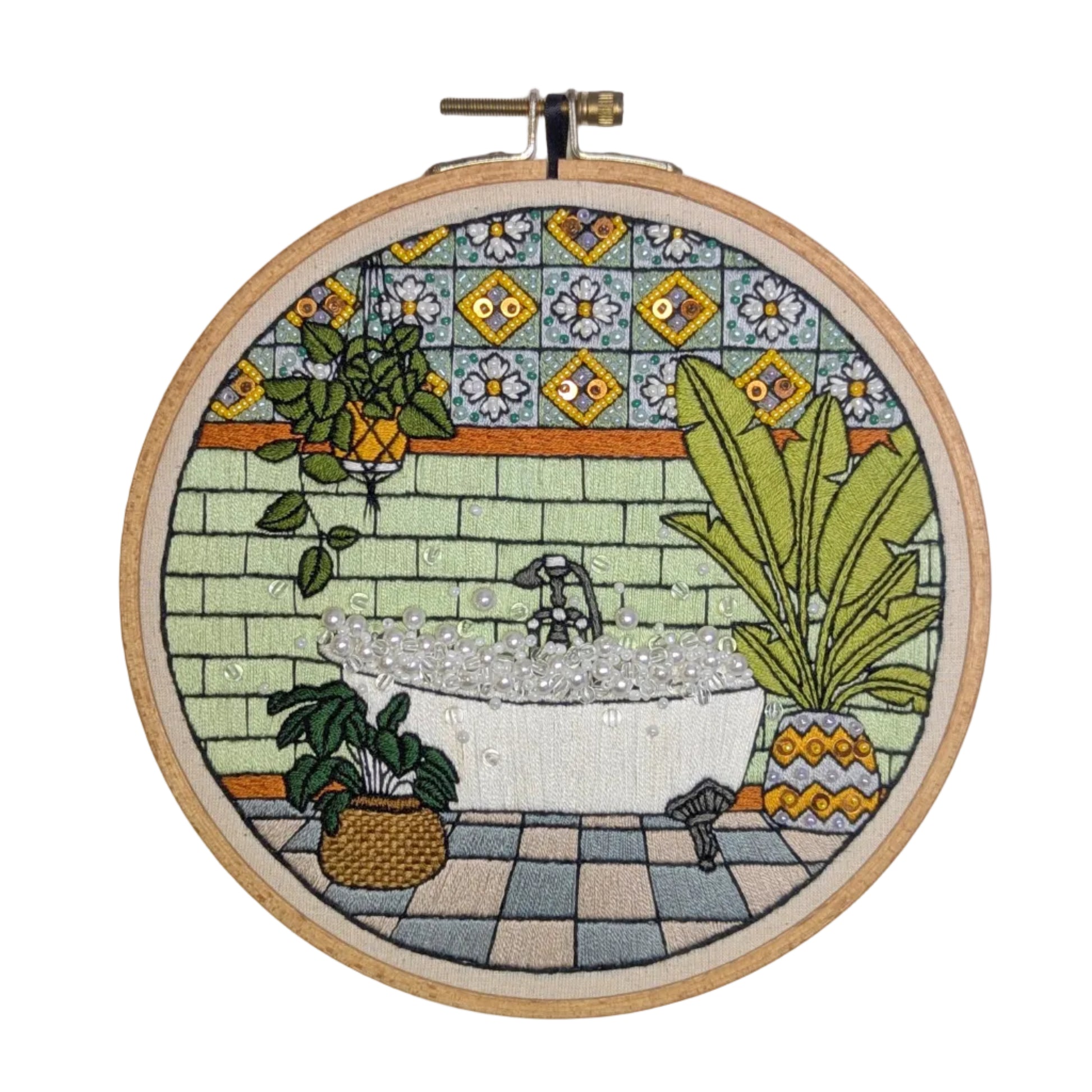 Embroidery hoop with a colorful depiction of a bathroom scene on a tiled background