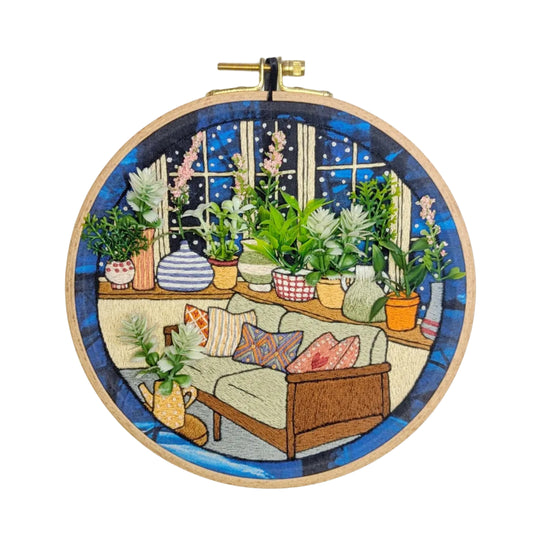 Embroidery hoop with a colorful depiction of a wintry conservatory scene.