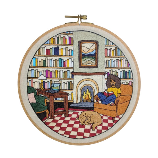Embroidery hoop with a colorful depiction of a cozy living room scene.