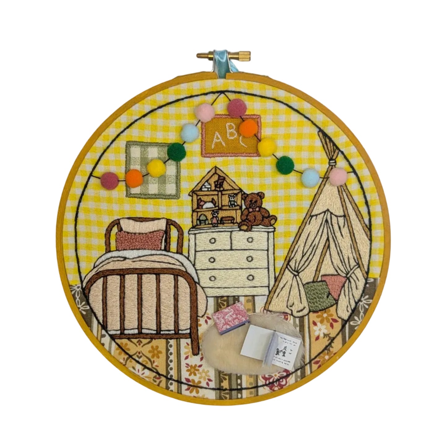 Embroidery hoop with a colorful children's room illustration on a yellow checkered background.