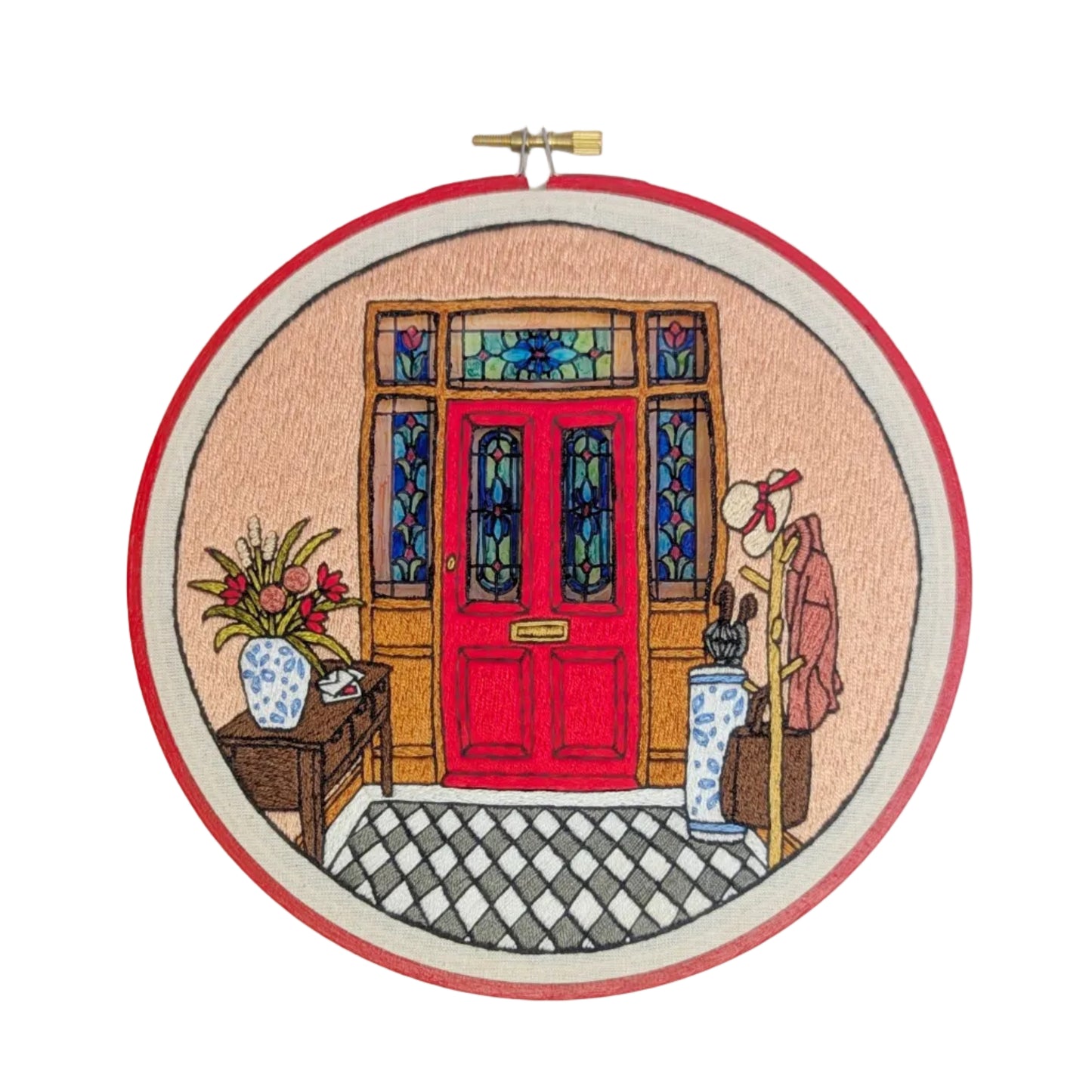 Embroidery hoop with a colorful depiction of a red door and doorsteps.